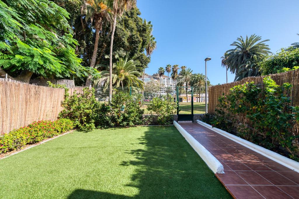 un giardino con prato e recinzione di Bungalow next to the Beach a Puerto Rico de Gran Canaria