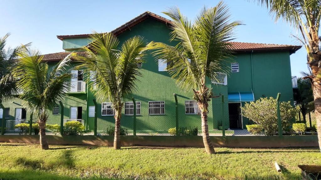 a green house with palm trees in front of it at Pousada Sintramog in Bertioga