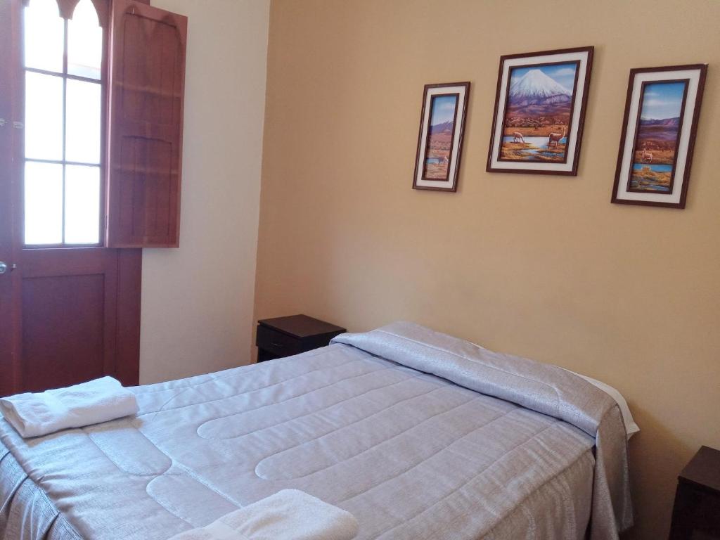 1 dormitorio con 1 cama y cuadros en la pared en Mango Hostel B&B, en Arequipa