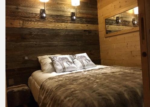 ヴァル・トランスにあるLes Appartements de Maéの木製の壁と照明が備わるベッドルーム1室