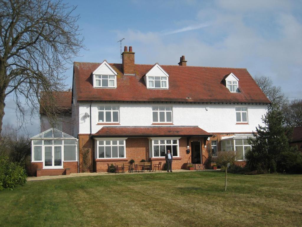 a person standing in front of a large house at Ashleigh House - HOT TUB, Snooker table, Sleeps 24 in Henley in Arden