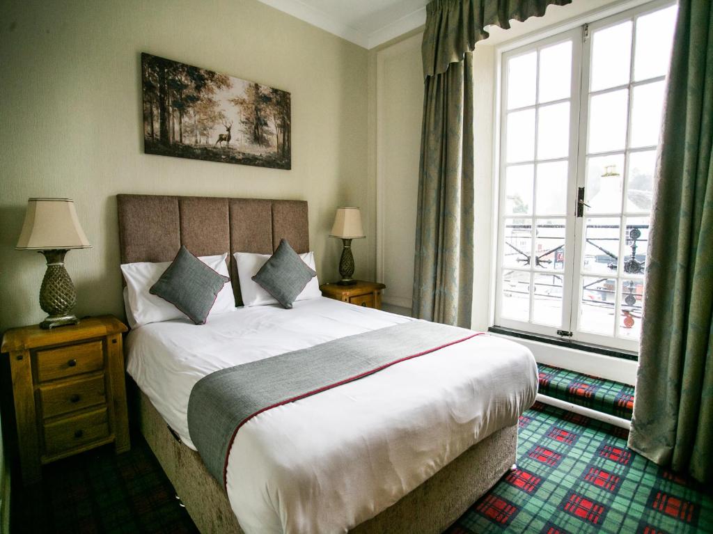 a bedroom with a large bed and a large window at The National Hotel in Dingwall