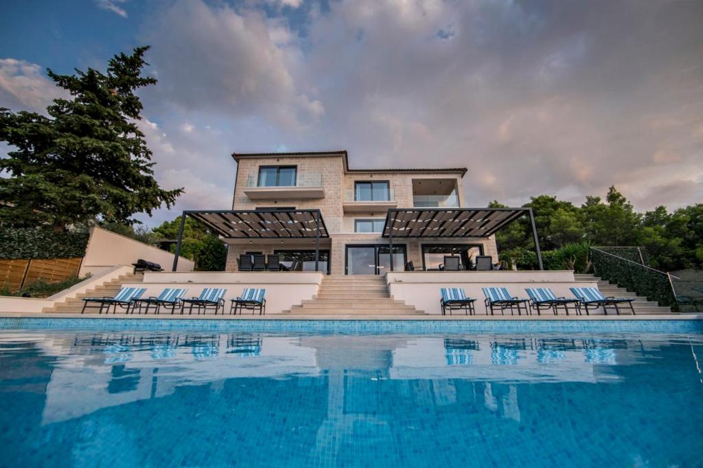 uma casa com piscina em frente a uma casa em Villa D em Postira