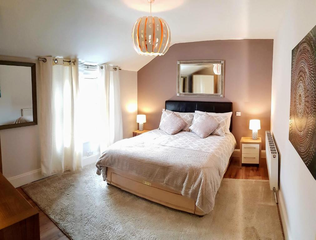 Cottage Grove Homestay rooms في بورتسماوث: غرفة نوم بسرير ومرآة وثريا
