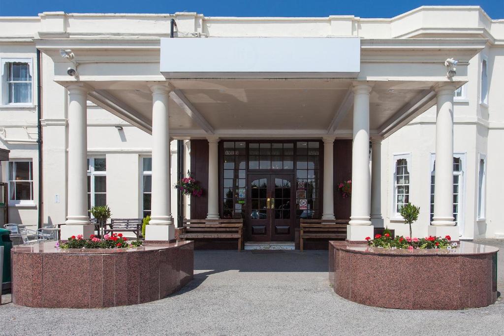 un edificio blanco con una gran entrada con flores en Russ Hill Hotel en Charlwood