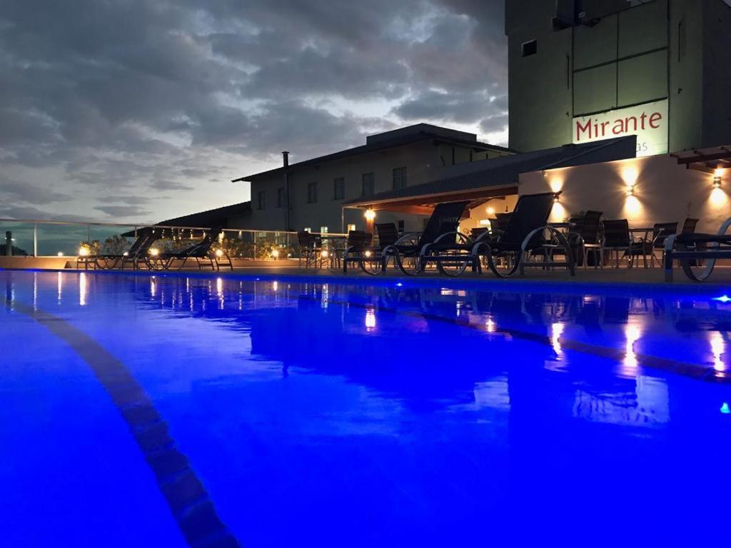 Hotel Mirante São Brás في São Brás do Suaçuí: حمام سباحة في الليل مع إضاءة زرقاء