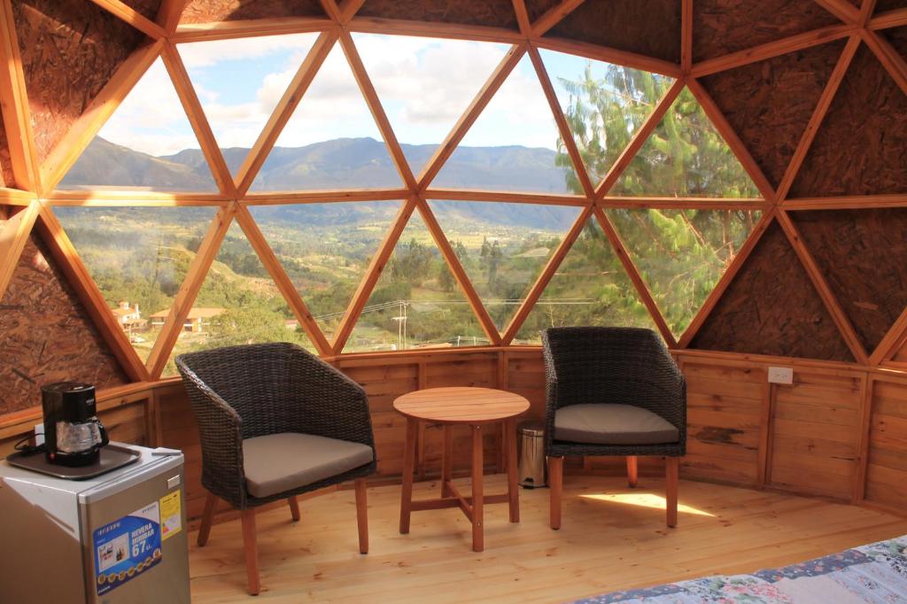 two chairs and a table in a room with a large window at Glamping y Chalet Aventura Park Villa De Leyva La Periquera in Villa de Leyva