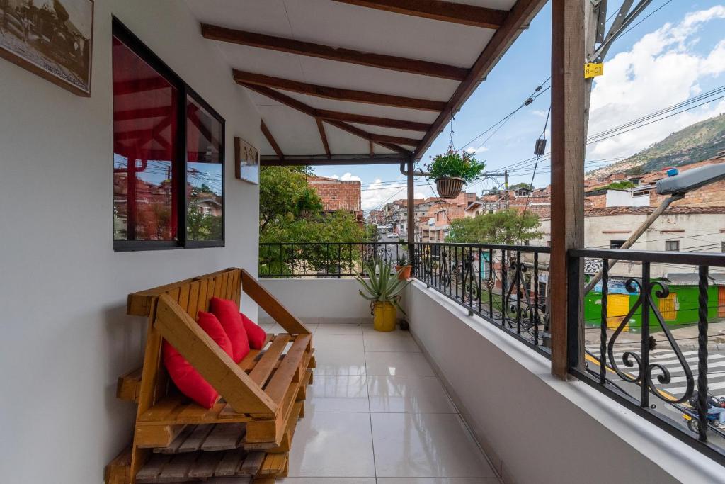 un balcón con un banco con almohadas rojas. en CAMPO VALDES PARK HOSTEL, en Medellín