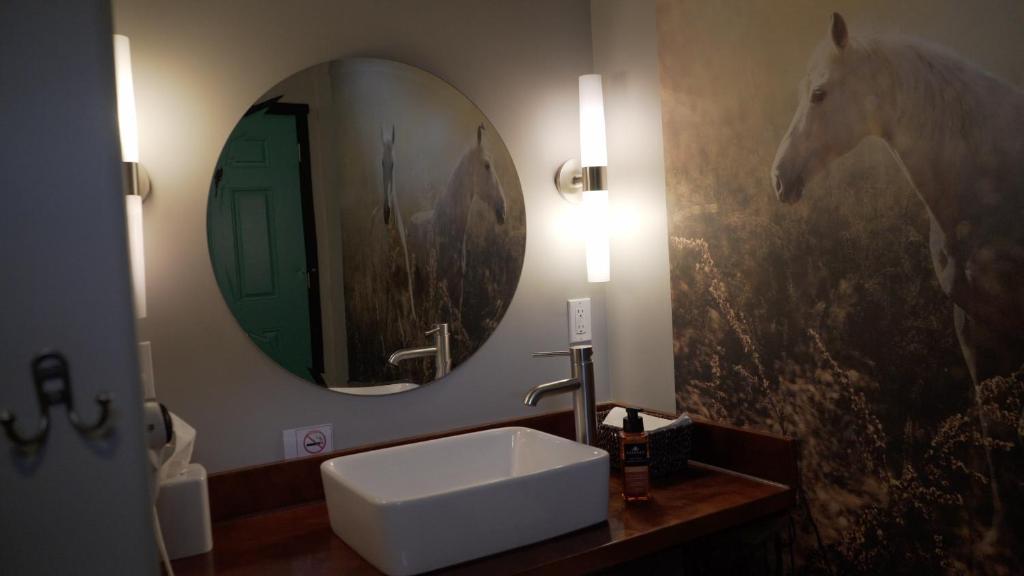 a bathroom with a sink and a mirror and a horse painting at Dreamcatcher Tipi Hotel in Gardiner