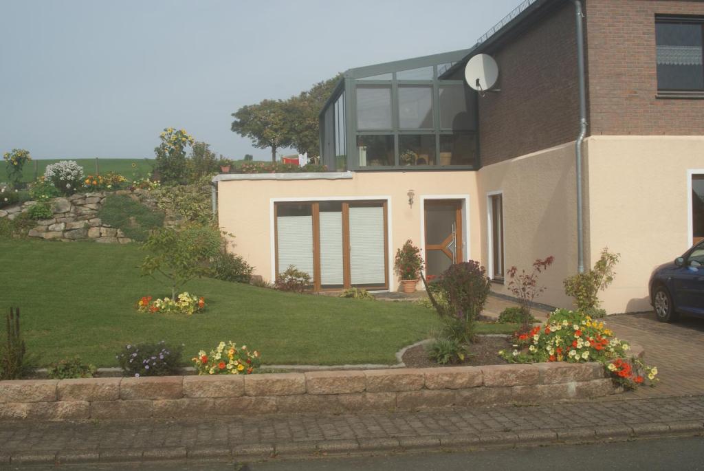 a house with a yard with flowers in front of it at Ferienwohnung Im Alftal, Bleialf in Bleialf