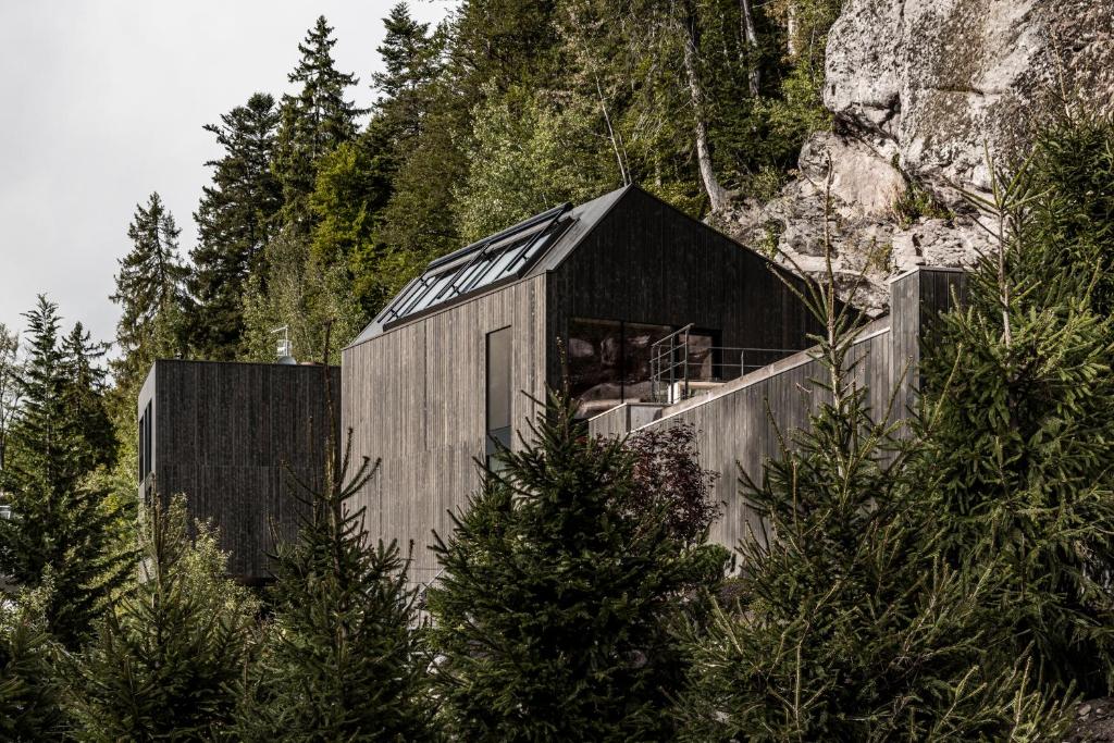 a house on a mountain with trees in front of it at Miramonti Boutique Hotel in Avelengo