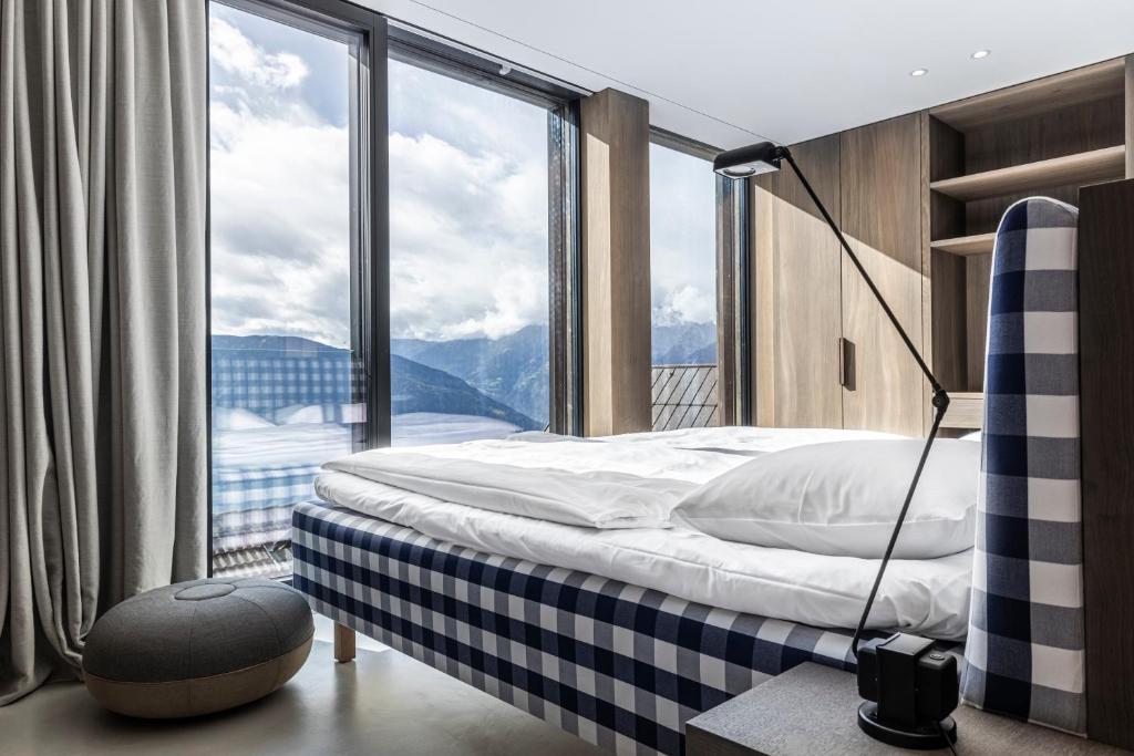 a bedroom with a bed and a large window at Miramonti Boutique Hotel in Avelengo