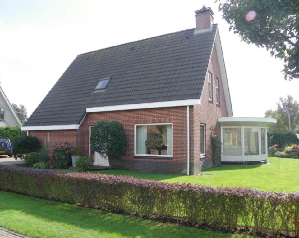 a red brick house with a black roof at Kroonstuk 2 in Nes