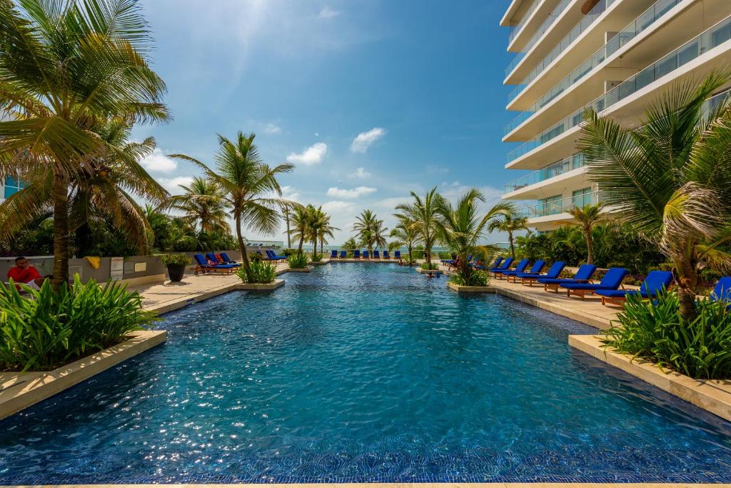 una piscina con sillas y palmeras y un edificio en Morros Epic 216, en Cartagena de Indias