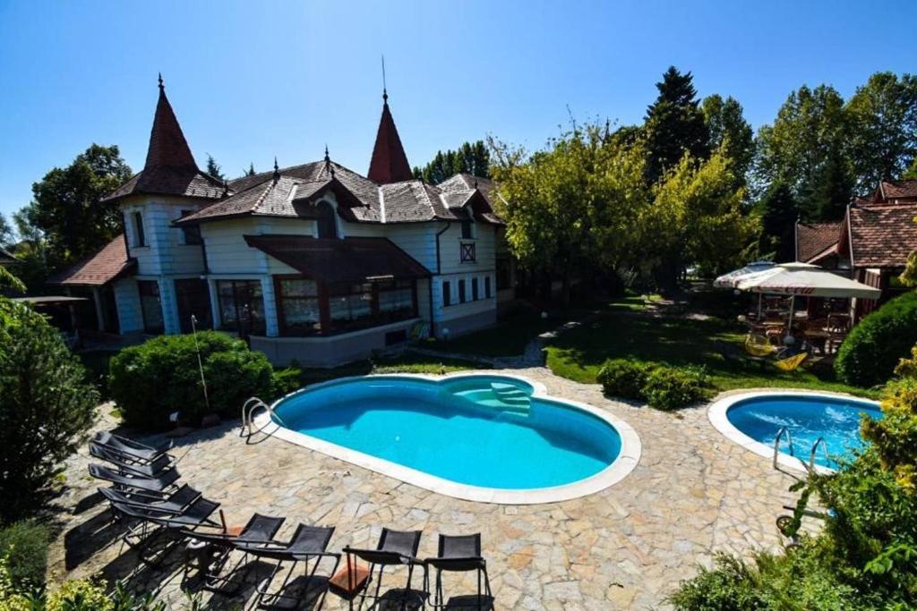 a swimming pool in front of a house at Garni Hotel Vila Milord Resort in Palić