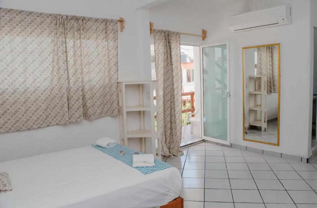 a small room with a bed and a window at Las Palmas in Zihuatanejo