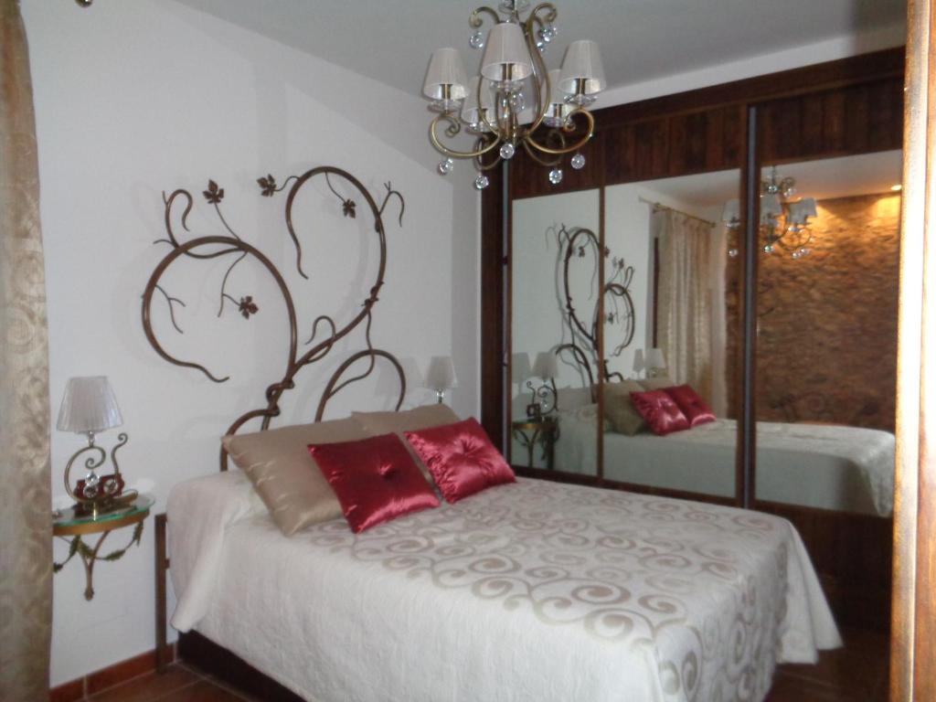 een slaapkamer met een bed met rode kussens en een spiegel bij Columbaira in Colomera