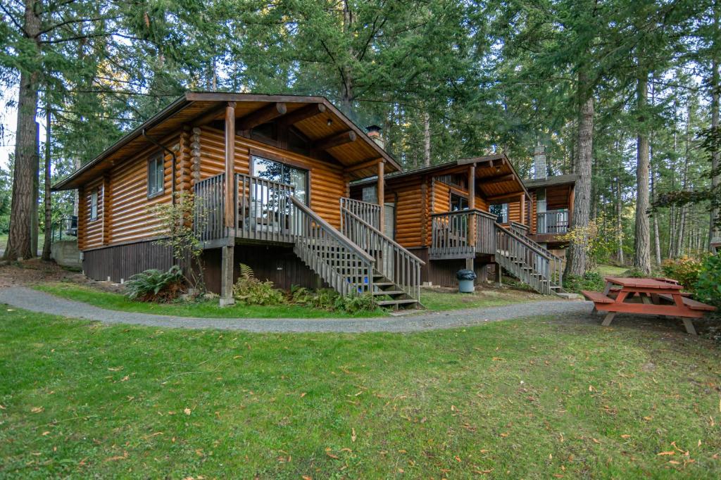 a log cabin in the woods with a picnic table at Cusheon Lake Resort in Ganges