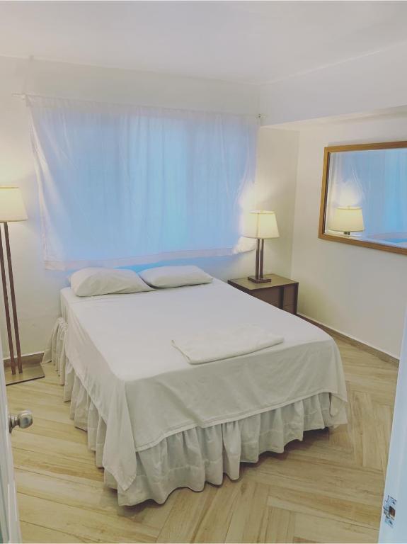 a bedroom with a white bed with a blue curtain at Palmira Hostel in Tegucigalpa
