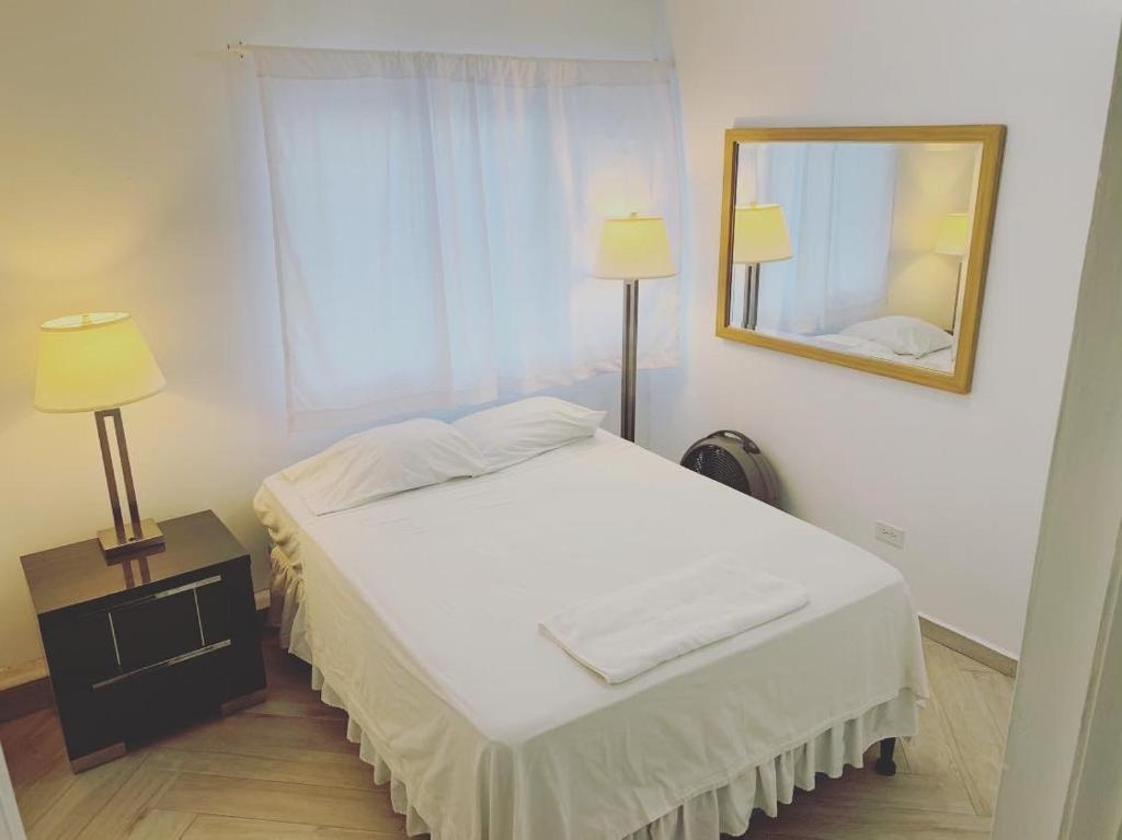 a bedroom with a bed with a mirror and lamps at Palmira Hostel in Tegucigalpa