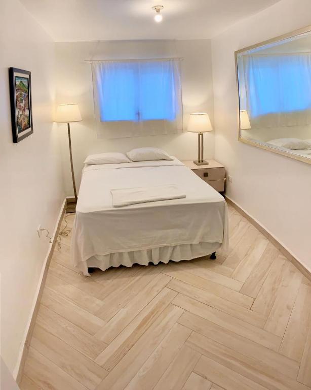 a white bedroom with a bed and a mirror at Palmira Hostel in Tegucigalpa