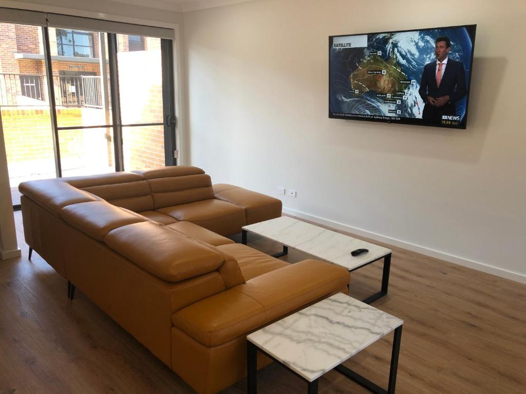 sala de estar con sofá y TV en la pared en The Grounds at Callaghan, en Jesmond