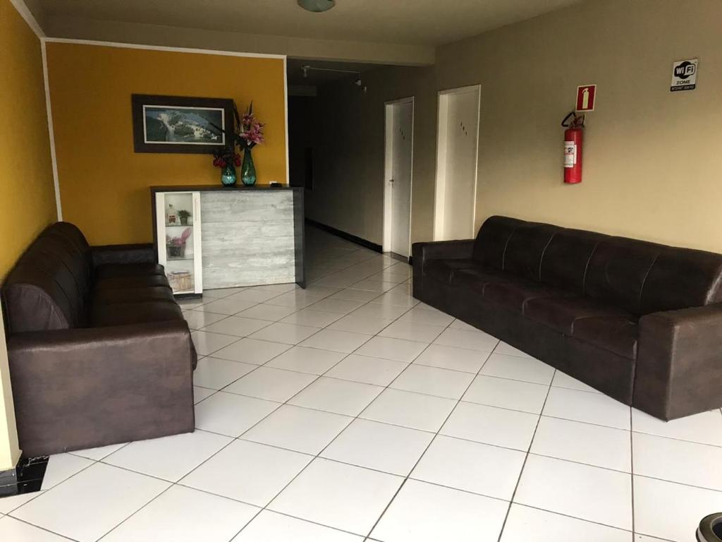 een woonkamer met 2 bruine leren banken en een open haard bij Carol Palace Hotel in Foz do Iguaçu