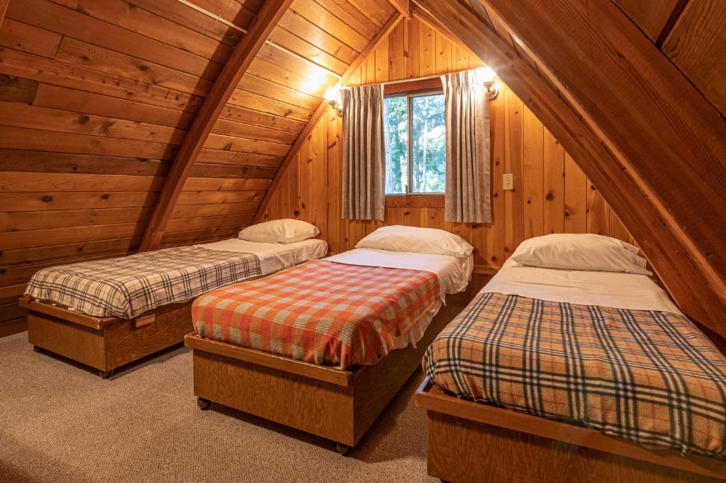 a bedroom with two beds in a wooden cabin at Cusheon Lake Resort in Ganges