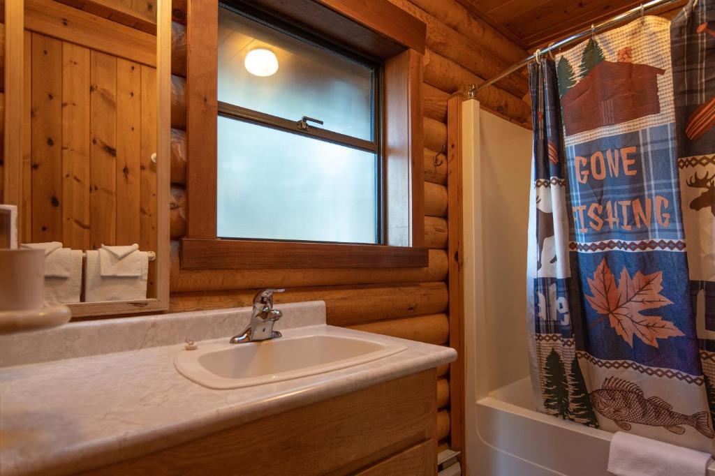 a bathroom with a sink and a window in a log cabin at Cusheon Lake Resort in Ganges