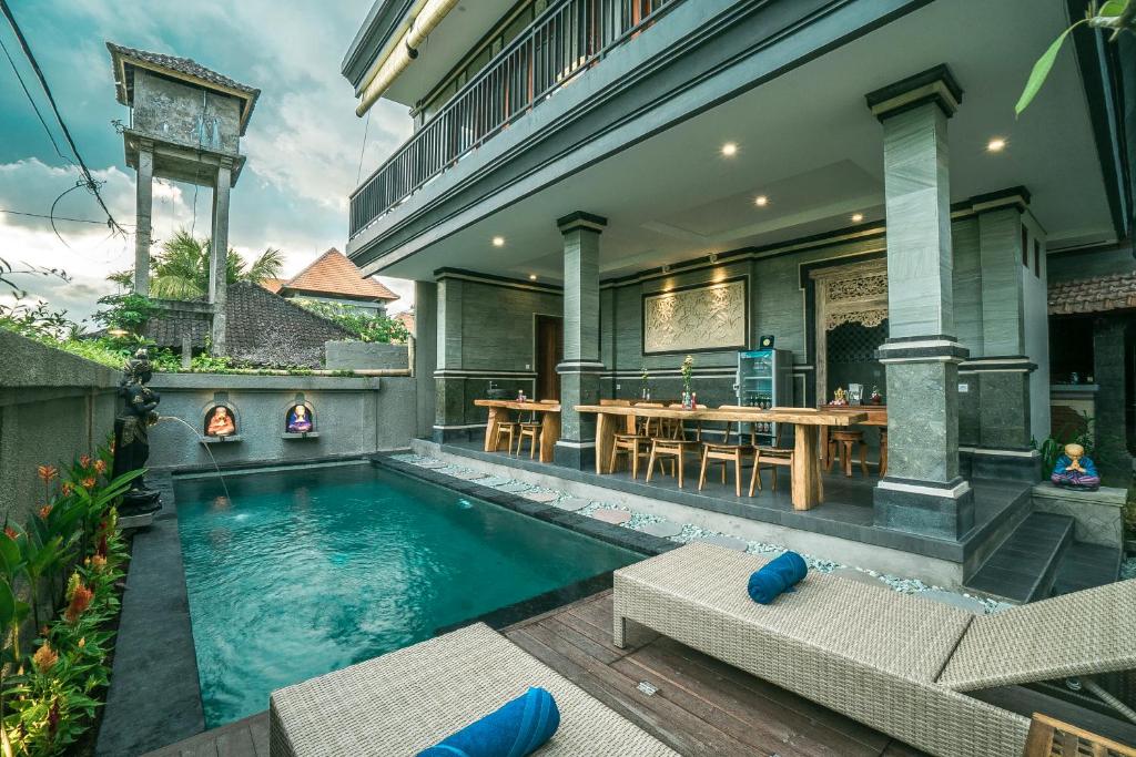 a house with a swimming pool and a dining area at Three Dewi's Guest House in Ubud