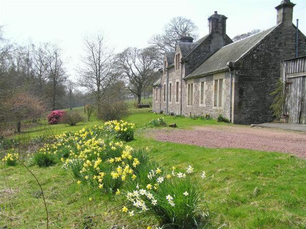 an old stone house with flowers in front of it at Laundry Cottage in Lanark