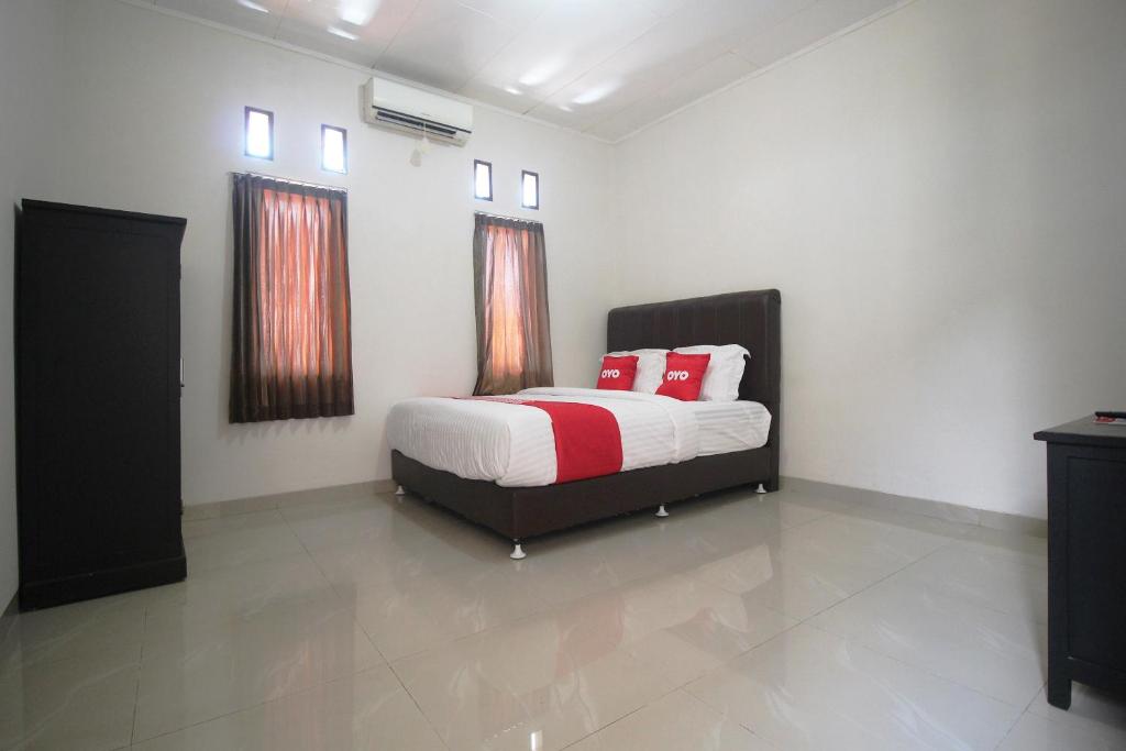 Un dormitorio con una cama con almohadas rojas. en OYO 1547 Wisma Ray Syariah, en Lampung