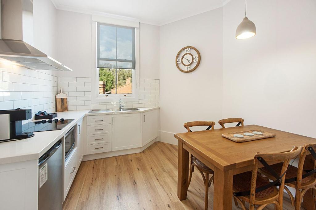 a kitchen with a table and a clock on the wall at Little Hopwood Apartment No1 in Echuca