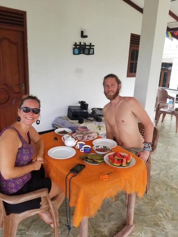 Un hombre y una mujer sentados en una mesa con comida. en Disna Place, en Unawatuna