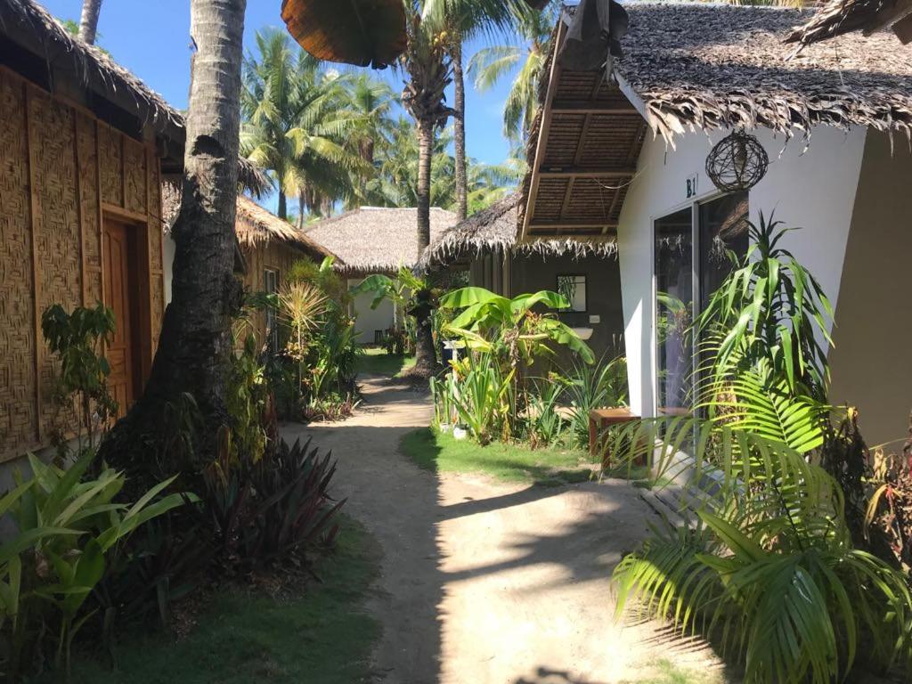 a pathway leading to a house with palm trees at Lukay Resort Siargao in General Luna