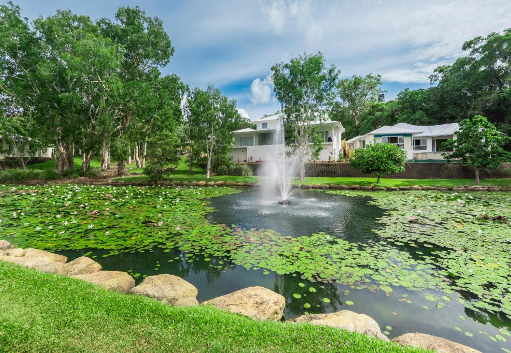 un estanque con una fuente frente a una casa en Coral Coast Resort Accor Vacation Club Apartments, en Palm Cove