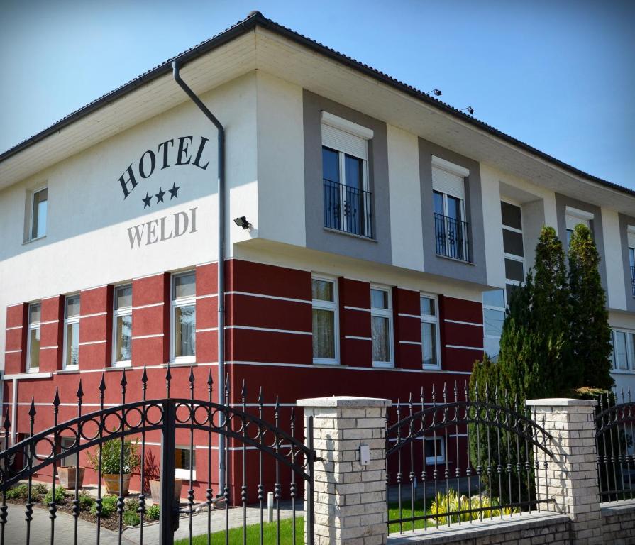 un bâtiment avec une clôture devant lui dans l'établissement Hotel Weldi, à Győr