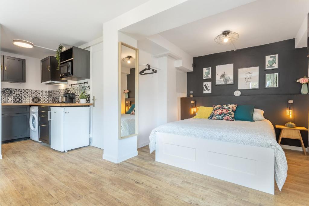 a bedroom with a white bed and a kitchen at Le Cocon Parilly in Bron