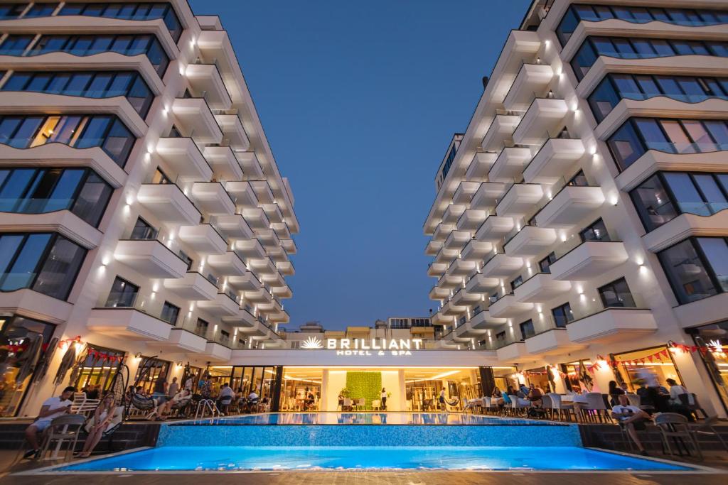 a hotel with a swimming pool in front of a building at Brilliant Hotel & SPA in Golem