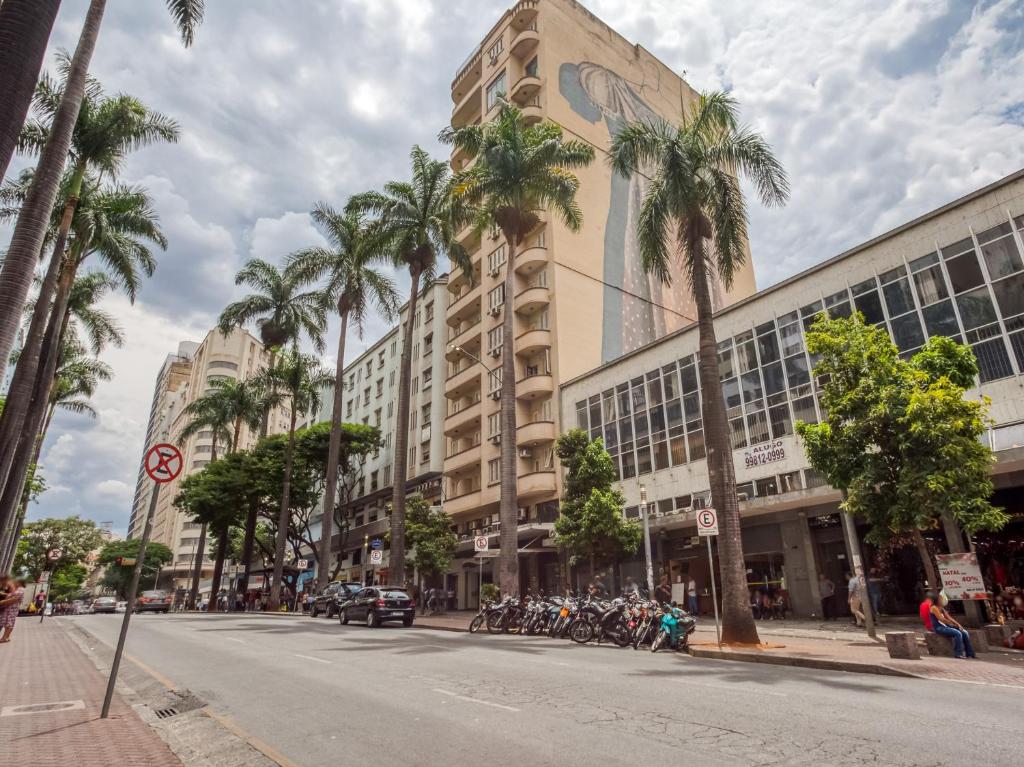 a city street with palm trees and a building at Amazonas Palace Hotel Belo Horizonte - By UP Hotel - Avenida Amazonas in Belo Horizonte