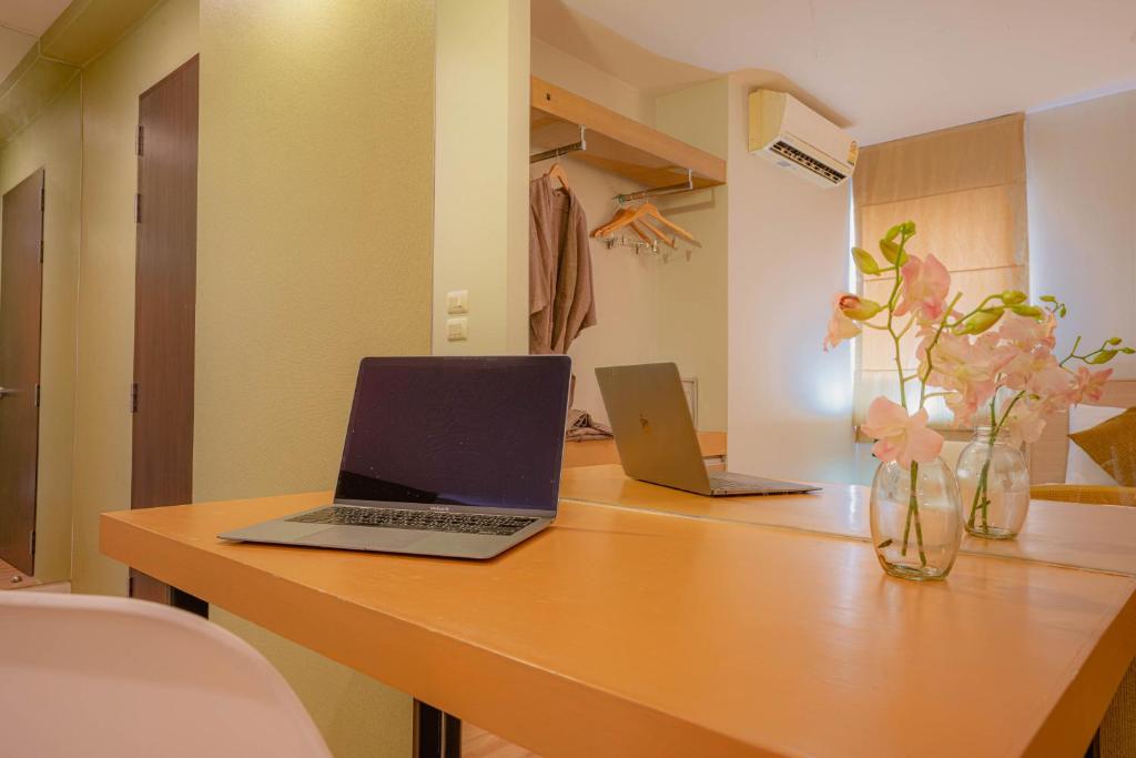 A built-in wooden desk with two laptops, a mirror, and an open hanging area behind it.