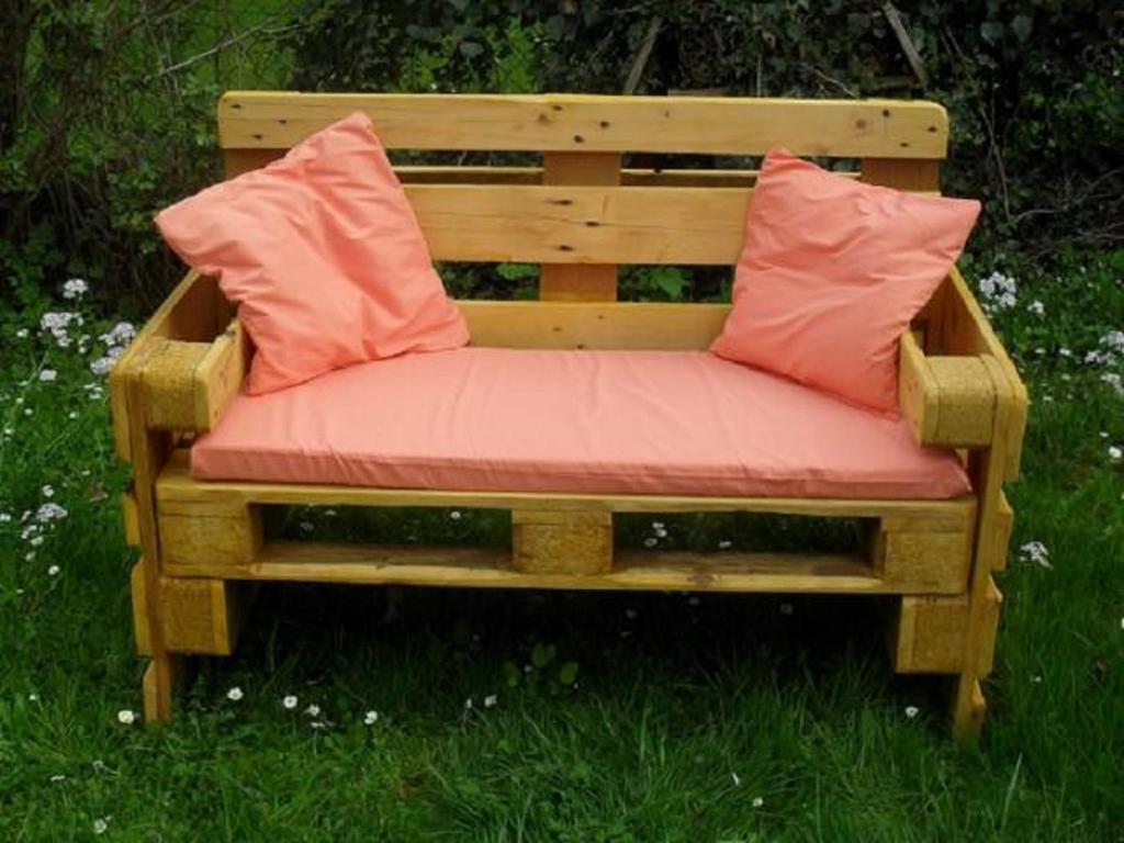 drewniana ławka z dwoma różowymi poduszkami w obiekcie Ferienwohnung Lahann w mieście Bokelrehm