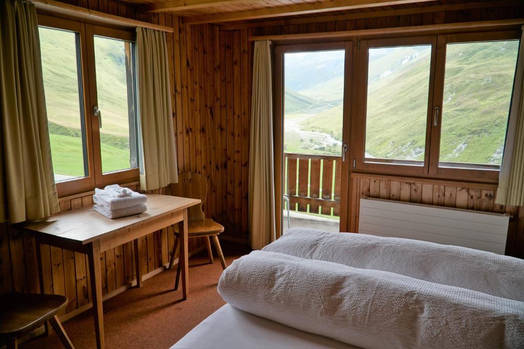 a bedroom with a bed and a desk and windows at Hotel Bergalga in Am Bach