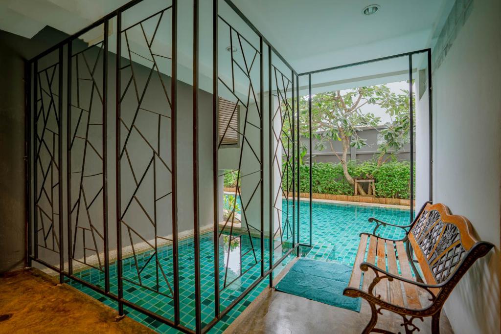 A covered poolside sitting area with a bench beside a glass-walled section.