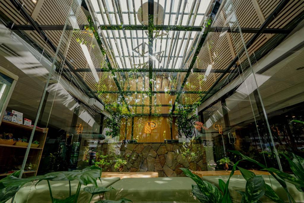 A glass-roofed, plant-filled hotel atrium frames a reception area and stone feature wall.