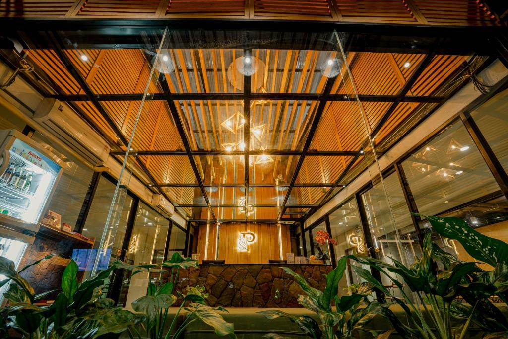 A plant-filled lobby reception area sits beneath a striking timber-and-glass ceiling.