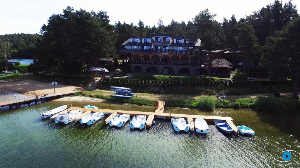 Wooden dock lined with small boats in front of resort shoreline, calm water reflections.