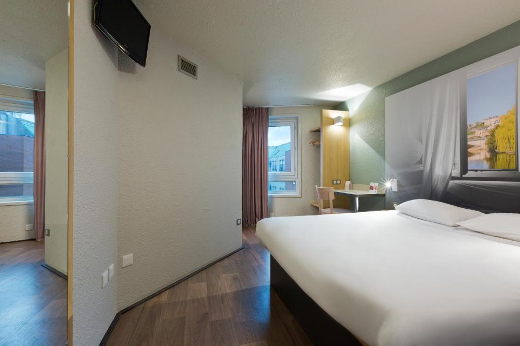 - une chambre avec un grand lit blanc et une fenêtre dans l'établissement B&B HOTEL le Mans Centre, au Mans
