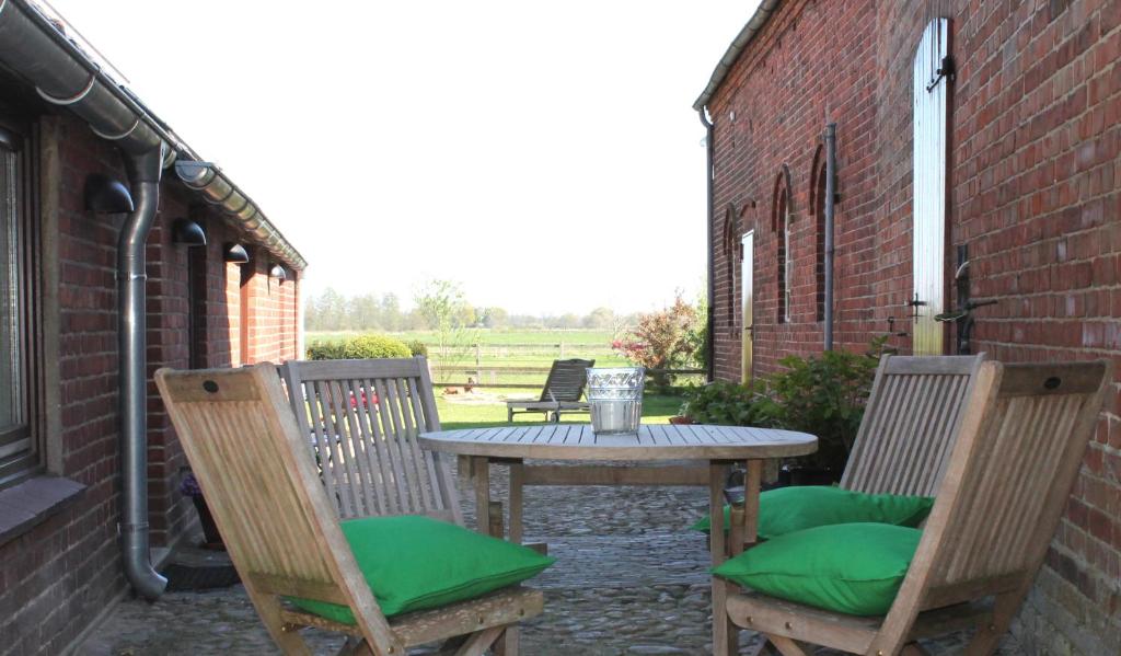 una mesa y 2 sillas con cojines verdes en el patio en Gretes Hof, en Osterholz-Scharmbeck