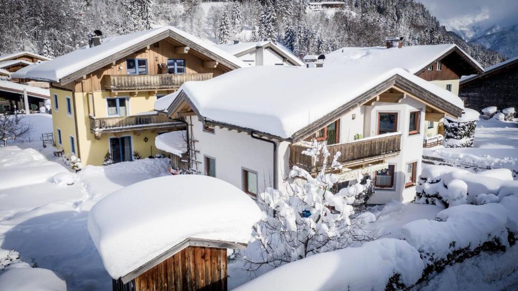 a house covered in snow in the mountains at Appartements Spielberg in Leogang
